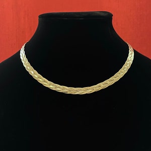 May include: A silver braided chain necklace on a black velvet display stand.