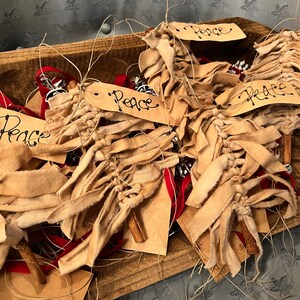 Op de afbeelding: Een verzameling handgemaakte kerstversiering van stof met kaneelstokjes en kaartjes met de tekst "Vrede".
