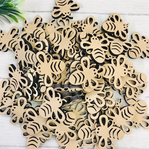 May include: A large collection of wooden bee cut-outs, ideal for crafting or decorating. The bees are all the same size and shape, with a simple, classic design. They are made of natural wood and have a light brown colour.