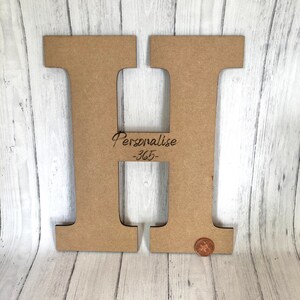 Pode incluir: Uma grande letra H de madeira marrom com a palavra "Personalizar" e o n&uacute;mero "365" gravados nela. A letra est&aacute; sobre uma superf&iacute;cie de madeira branca.