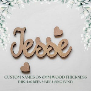 May include: Wooden name "Jesse" in a cursive font, accompanied by two heart shapes. The name and hearts are in a light brown color. Text at the bottom reads "CUSTOM NAMES ON 6MM WOOD THICKNESS THIS HAS BEEN MADE USING FONT 1."