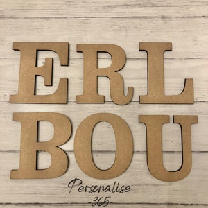 May include: Six individual capital letters made of light brown wood, arranged in two rows. The top row displays the letters E, R, and L, while the bottom row shows B, O, and U. Below the letters, the text Personalise 365 is written in black script.