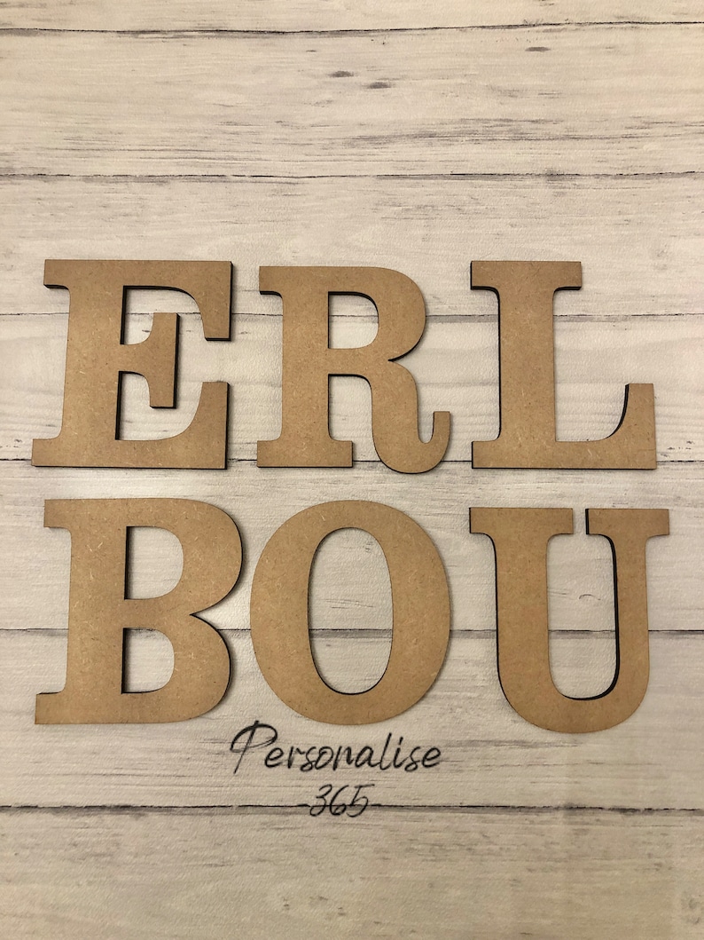 May include: Six individual capital letters made of light brown wood, arranged in two rows. The top row displays the letters E, R, and L, while the bottom row shows B, O, and U. Below the letters, the text Personalise 365 is written in black script.