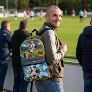 以下が含まれることがあります： サッカーボールと「WORLD CUP 2026」の文字が入ったカラフルなバックパック。 バックパックには、旗とサッカー場がデザインされています。 バックパックは人が背負っています。