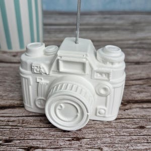 Könnte beinhalten: Ein Set aus drei Keramikbechern mit gesprenkelter, matter Oberfläche. Die Becher sind in den Farbtönen Creme, Hellgrau und Dunkelgrau gehalten. Jeder Becher hat ein schlichtes, minimalistisches Design und einen abgerundeten Henkel.
