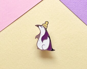 White king penguin with purple wing and yellow hat. Enamel pin.