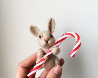 Felted toy, a rabbit holding Candy cane in its paws