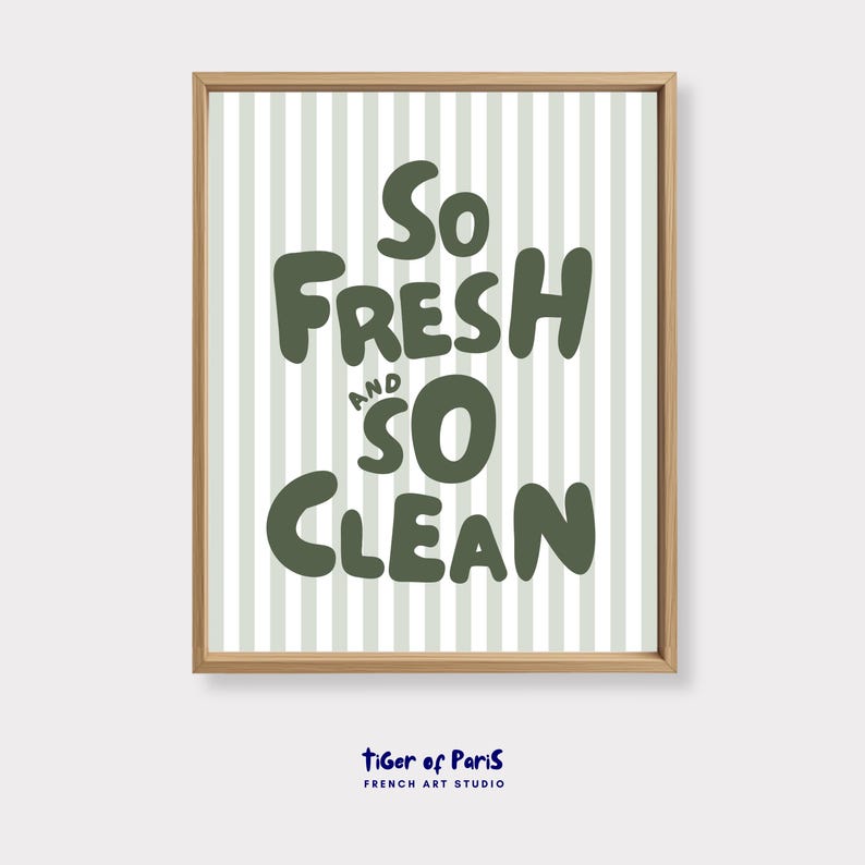 May include: A framed print with the words "So Fresh and So Clean" in dark green, bold letters. The background features vertical light green and white stripes. The frame is a light brown color. The text "tiger of Paris FRENCH ART STUDIO" is at the bottom.