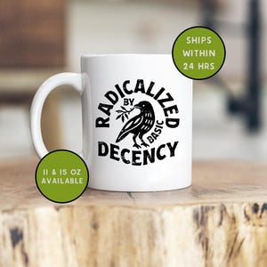 May include: White ceramic mug with a black graphic of a bird holding a sprig, surrounded by the words "RADICALIZED BY BASIC DECENCY." The mug is available in 11 and 15 oz sizes.