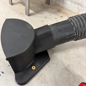 Może przedstawiać: Czarny, drukowany w 3D osprzęt do odkurzacza z zakrzywioną głowicą i elastycznym wężem. Osprzęt ma płaską podstawę z małą, złotą śrubą. Wąż jest żebrowany i łączy się z osprzętem.