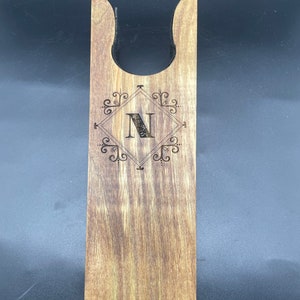 Könnte beinhalten: Ein Holz-Stiefelknecht mit einem dekorativen Design und dem eingravierten Buchstaben "N".