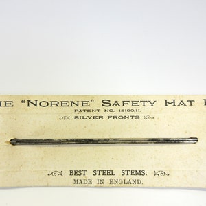 May include: Vintage "Norene" safety mat pins on a cream-colored card. The card reads "The 'Norene' Safety Mat Pin" with "Silver Fronts" and "Best Steel Stems. Made in England." The pins are silver.