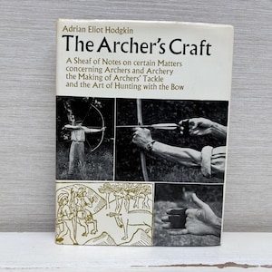 May include: A vintage book titled "The Archer's Craft" by Adrian Eliot Hodgkin. The cover features black and white images of archery, including a person drawing a bow and arrow. The book's title and author are in black text on a white background.