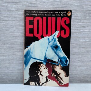 May include: A paperback book cover with a red title "EQUUS" and a photo of a white horse and two people. The text below the title reads "Peter Shaffer's stage masterpiece, now a superb film starring Richard Burton and Peter Firth."