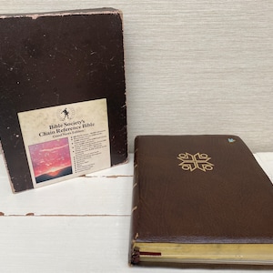 Könnte beinhalten: Eine braune, ledergebundene Bibel mit goldenen Verzierungen und dem Text "Bible Society's Chain Reference Bible Good News Edition" auf dem Einband.