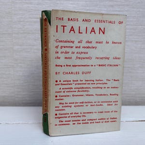 May include: Vintage book titled "The Basis and Essentials of Italian" by Charles Duff. The cover is off-white with red text, and the spine is green. The book promises to teach grammar and vocabulary.