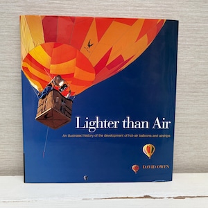 May include: A blue book cover with the title "Lighter than Air" in white text. The book cover features a colorful hot air balloon with a basket and a blue sky background. The text "An illustrated history of the development of hot-air balloons and airships" is below the title. The author's name, "David Owen", is at the bottom of the cover.