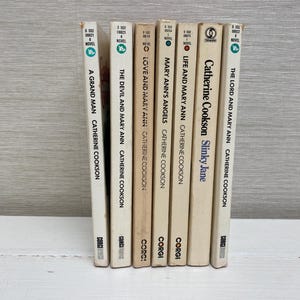 Puede incluir: Una colección de siete libros de bolsillo de Catherine Cookson. Los libros son todos blancos con texto negro y tienen el logotipo de Corgi en el lomo. Los títulos son "The Lord and Mary Ann", "Slinky Jane", "Life and Mary Ann", "Mary Ann's Angels", "Love and Mary Ann", "The Devil and Mary Ann" y "A Grand Man".