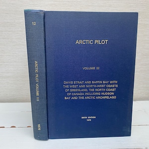 Könnte beinhalten: Ein blaues Hardcover-Buch mit dem Titel "Arctic Pilot" Band III, Sechste Auflage 1976. Das Buch behandelt die Davis-Straße und die Baffin-Bucht mit der West- und Nordwestküste Grönlands, der Nordküste Kanadas einschließlich der Hudson Bay und der Arktischen Inselgruppe.