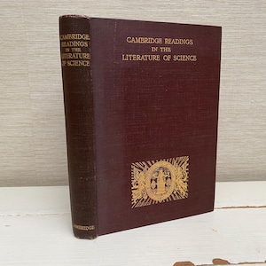 May include: A maroon hardback book titled "Cambridge Readings in the Literature of Science." The spine is a darker shade of maroon. Gold lettering and a gold emblem are visible on the cover. The book is standing upright.