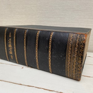 May include: A black leather-bound Holy Bible with gold-colored lettering and decorative accents.