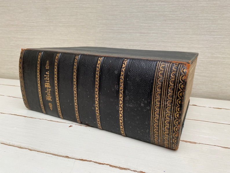 May include: A black leather-bound Holy Bible with gold-colored lettering and decorative accents.