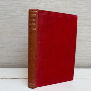 May include: A vintage book with a red cover and a brown spine. The spine features gold lettering that reads "Catullus Select Poems" and the author's name. The book is standing upright against a light-colored background.