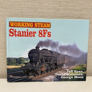 May include: A book titled "Working Steam Stanier 8Fs" with a black and red title on a light blue background. The cover features a black steam locomotive with a plume of smoke, pulling a train of boxcars on a track.