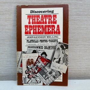 Peut inclure: Un livre marron intitulé "Discovering Theatre Ephemera" de John Kennedy Melling. La couverture du livre présente des images d'affiches de théâtre, de photos, de billets, de dessins animés, d'autographes, de reliques, de programmes et de dessins d'époque.
