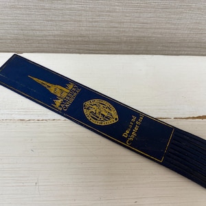 May include: A navy blue bookmark with gold lettering and a gold illustration of a cathedral. The bookmark has the text "Salisbury Cathedral" and "Dean and Chapter Seal". The bottom edge has several navy blue tassels.