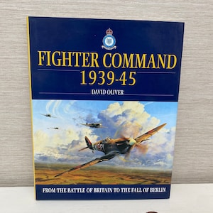 Op de afbeelding: Een boek getiteld "Fighter Command 1939-45" door David Oliver. De omslag toont een schilderij van een jachtvliegtuig uit de Tweede Wereldoorlog in de vlucht. De tekst "From the Battle of Britain to the Fall of Berlin" staat onderaan de omslag gedrukt.