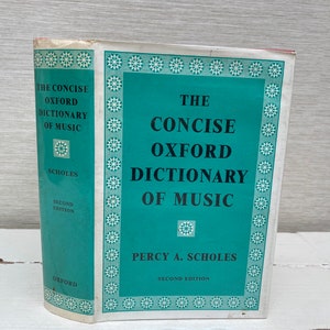 Peut inclure: Un livre relié de couleur bleu sarcelle intitulé "The Concise Oxford Dictionary of Music" de Percy A. Scholes. Le livre est une deuxième édition et présente une bordure décorative d'étoiles blanches sur un fond bleu sarcelle.