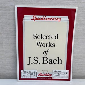 May include: A rectangular book cover with a red border and the title "Selected Works of J.S. Bach" in large black letters. The cover also features the text "SpeedLearning" and "the Buckley notation system".