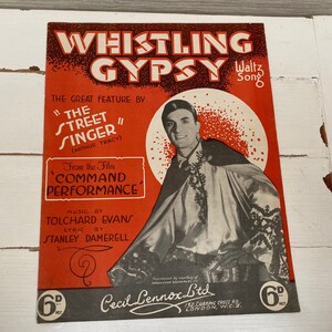 Puede incluir: Una portada de partitura vintage para la canción "Whistling Gypsy" de la película "Command Performance". La portada presenta una foto en blanco y negro de un hombre con un disfraz, con el título de la canción en letras rojas grandes.