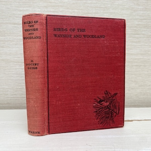 Könnte beinhalten: Ein rotes Hardcover-Buch mit dem Titel "Birds of the Wayside and Woodland" mit einem Pocket-Guide-Etikett und einer Schwarzweißillustration eines Vogels auf einem Ast auf dem Einband.