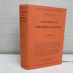 Può includere: Un libro di testo arancione intitolato "Textbook of Pharmacognosy" di T.E. Wallis. La copertina del libro presenta testo nero e le parole "Fourth Edition". Il libro è in piedi su una superficie di colore chiaro.