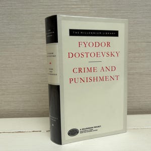 May include: A hardcover book titled "Crime and Punishment" by Fyodor Dostoevsky. The book has a white cover with red text and a black spine. The book is part of "The Millennium Library" series.