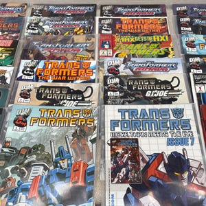 May include: A collection of various Transformers comic books, featuring vibrant covers with robot characters and action scenes. Titles include "The War Within" and "More Than Meets The Eye". The comics are displayed in protective sleeves.