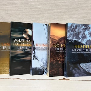 Può includere: Una collezione di cinque libri con copertina rigida e vari design. I libri presentano titoli e nomi di autori, tra cui "Pied Piper" e "What Happened to the Corleones". Le copertine mostrano immagini di paesaggi e arte astratta.
