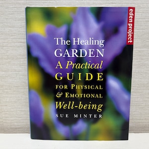 May include: A book titled "The Healing Garden: A Practical Guide for Physical & Emotional Well-being" by Sue Minter. The cover features a blurred floral background with purple and yellow hues, and the text is in white and yellow.