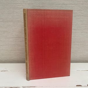 May include: A red hardback book with the title "Oscillations of the Earth's Atmosphere" by "H.W. Wilkes" on the spine.