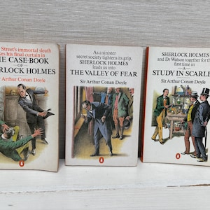 May include: Three vintage paperback books by Sir Arthur Conan Doyle featuring Sherlock Holmes. Titles include "The Case-Book of Sherlock Holmes", "The Valley of Fear", and "A Study in Scarlet". Each book has a unique cover illustration.