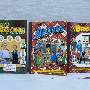 Pode incluir: Três capas de banda desenhada coloridas com as personagens de banda desenhada "The Broons". As capas são vermelhas, castanhas e azuis com um padrão de xadrez. O texto nas capas diz "The Broons" e "Scotland's Happy Family".