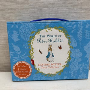 Peut inclure: Un coffret bleu clair avec "Le Monde de Pierre Lapin" de Beatrix Potter. La couverture présente Pierre Lapin et des papillons. L'ensemble comprend 5 histoires classiques de Pierre Lapin et une poignée bleue.
