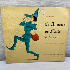 May include: A vintage children's book cover featuring an illustration of a whimsical character playing a flute. The book is titled "Le Joueur de Flûte de Hamelin" by Samivel. The cover is yellow with a light blue and green illustration.