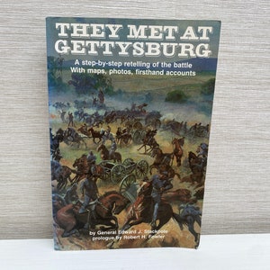 May include: Book cover with a painting of a Civil War battle scene. The title is "They Met at Gettysburg: A step-by-step retelling of the battle with maps, photos, firsthand accounts." The author is General Edward J. Stackpole with a prologue by Robert H. Fowler.