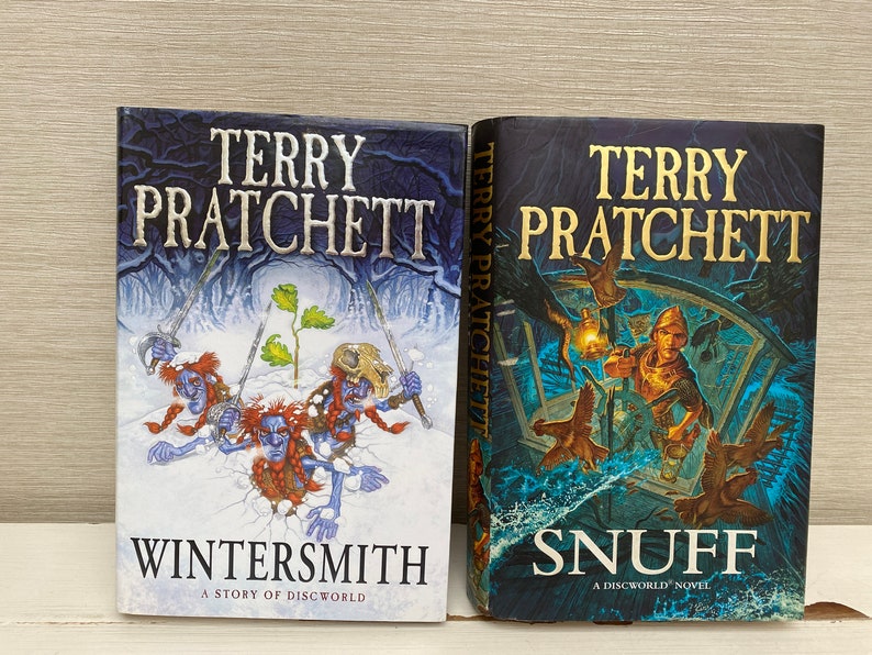 May include: Two paperback books by Terry Pratchett, "Wintersmith" and "Snuff", both featuring fantasy illustrations on the covers.