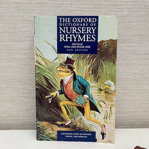 Puede incluir: El Diccionario Oxford de Rimas Infantiles, un libro con una nueva edición, que incluye más de 500 rimas, canciones y acertijos. La portada presenta una ilustración de una rana con traje y sombrero de copa, caminando por un pantano.