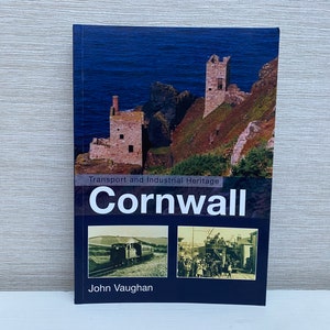 Könnte beinhalten: Ein blaues Buch mit dem Titel "Transport and Industrial Heritage Cornwall" von John Vaughan. Der Umschlag zeigt ein Foto von zwei Steintürmen auf einer Klippe mit Blick auf das Meer und zwei kleinere Fotos von einem Zug und einer Gruppe von Menschen.