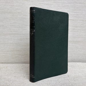 May include: A dark green hardcover book with the title visible on the spine. The book has a textured cover and appears to be in good condition. The book is standing upright on a light-colored surface.